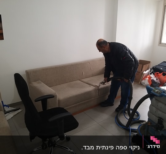 אדם מנקה ספה עם מכונת ניקוי מקצועית